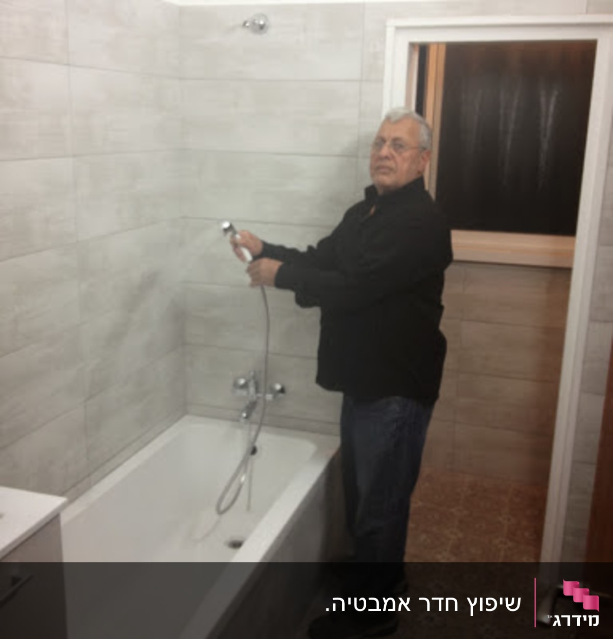 אדם מחזיק צינור מקלחת בחדר אמבטיה משופץ